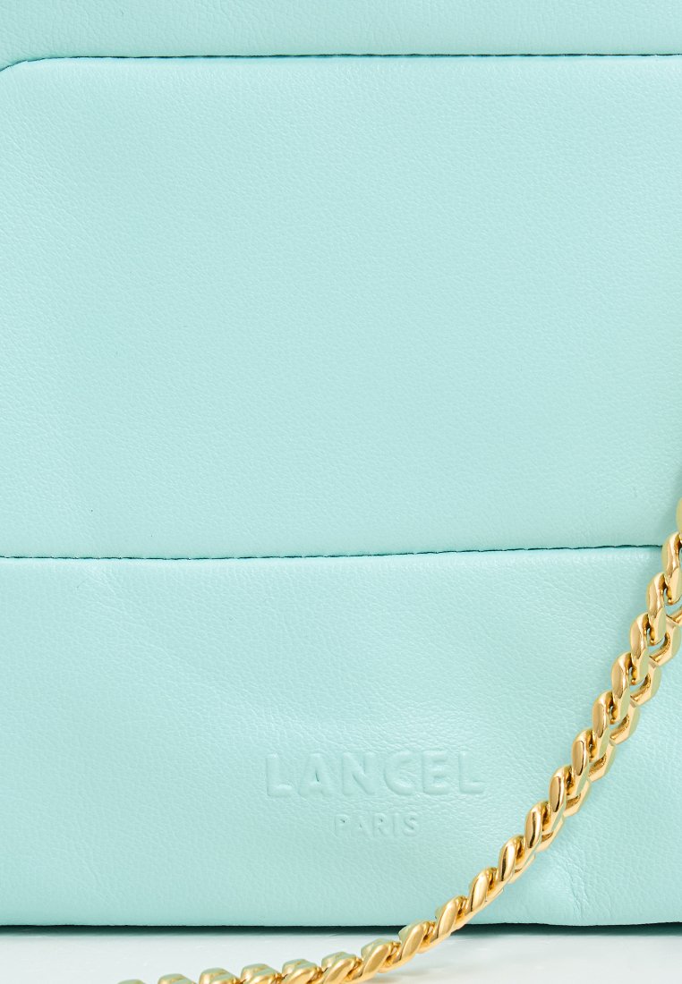 Jasnoniebieska skórzana torebka na ramię z złotym łańcuchem i wytłoczonym logo "LANCEL PARIS" na dole. Gładka tekstura o minimalistycznym wzornictwie.