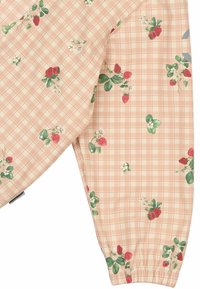 Haut à manches longues présentant un motif à carreaux roses avec des fraises rouges et des feuilles vertes. Poignets élastiques et texture de tissu lisse.