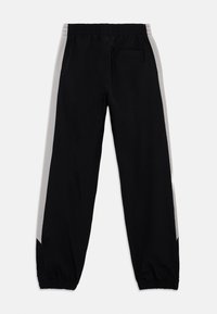 Pantalones jogger negros hechos de tela ligera, con franjas laterales grises, cintura elástica y puños elásticos en los tobillos.