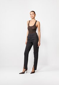 Pruun ribituba keha sobitatud hallide kohandatud pükstega, mis on kaunistatud peene ruudustikuga, küljeslate ja sädelusega, millele lisavad sära läikivad kontsad.