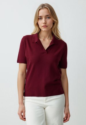 Bordeaux kortarmige polo met kraag, met een zachte textuur en een getailleerde snit. Draagt u met lichtgekleurde broeken.