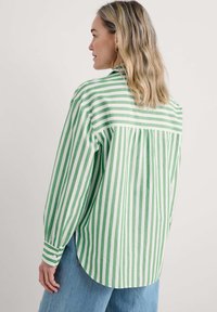 Camicia a righe verdi e bianche con una vestibilità comoda, caratterizzata da maniche lunghe, polsini con bottoni e un design posteriore plissettato.