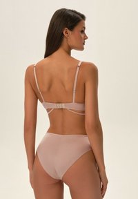 Jasnoróżowy komplet bielizny składający się z biustonosza na zapięcie z tyłu z regulowanymi ramiączkami oraz gładkich, wysokich majtek. Gładka tekstura materiału.