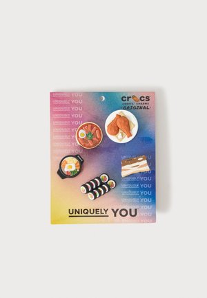 Fem miniature mad-tema Crocs Jibbitz-vedhæng på et farverigt "Uniquely You" kort inklusive sushi, kyllingelår og dessert.