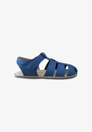 Sandalia azul de cuero con puntera cerrada, correa ajustable de velcro y plantilla con textura de corcho, mostrada de lado sobre fondo blanco.