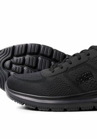 Chaussures de sport noires avec dessus en tissu texturé, lacets à l'avant, semelles épaisses et rembourrées, et motif sur la semelle extérieure, logo latéral visible.