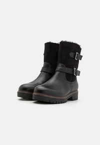 Botas de cuero negras hasta el tobillo con acentos de ante, dos hebillas ajustables, una suela texturizada y un tacón ligeramente elevado.
