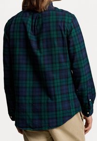 Ruudutettu paita tumman vihreänä ja laivastonsinisenä, flanellimateriaalia, pitkät hihat, pyöreä helma, nappikäänteet, jossa on koko paidan kattava ruutukuvio.