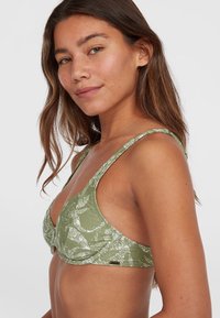 Top bikini verde a fantasia con spalline larghe, forma a triangolo e una leggera lucentezza nella texture del tessuto.