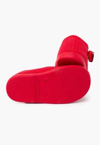 Zapato rojo con un upper texturizado, acento de hebilla circular y suela de goma sólida. Diseñado con un talón cerrado y plantilla acolchada para mayor comodidad.