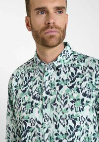 Korte mouwen overhemd in een groen en marineblauw luipaardpatroon. Voorzien van een button-down kraag en lichtgewicht stof met een gladde textuur.