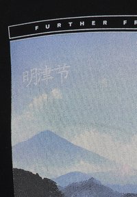 Tessuto nero con un grafico di paesaggio montano in tonalità di blu e grigio, con testo bianco sopra che recita "ULTERIORI FR...".