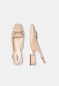 Beige patent leather slingback shoes with a square toe, small block heel, silver hardware detail, and an adjustable ankle strap.