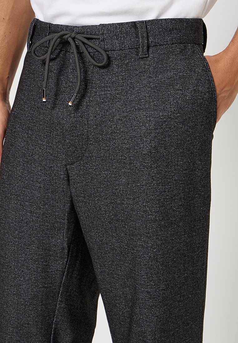 Graue, strukturierte Hose mit einem elastischen Bund und Kordelzugverschluss. Sie zeichnet sich durch eine glatte Oberfläche und ein dezentes Fischgrätmuster aus.