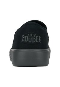 Schwarzer Canvas-Schuh mit rundem, flachem Design. Verfügt über eine strukturierte graue Gummisohle und ein gesticktes "HEY DUDE"-Logo an der Ferse.