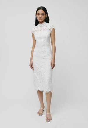Rochie albă din dantelă, cu guler înalt și mâneci scurte, decorată cu modele florale complicate și un tiv ondulat, asortată cu pantofi cu barete.