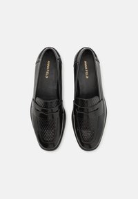 Svarta läderloafers med ett strukturerat vävt mönster på framsidan, med en slät läderrem och rundad tådesign.