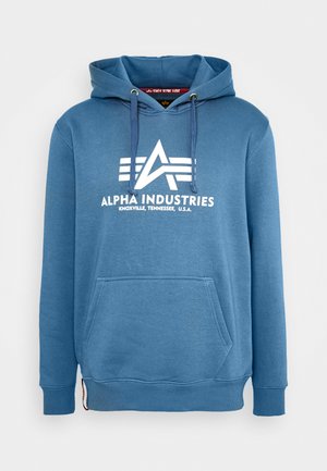 Un hoodie bleu en matière douce, doté d'une poche frontale, d'une capuche avec cordon et d'un logo blanc avec des rayures horizontales.