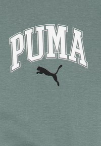 Sweatshirt en coton vert avec "PUMA" en lettres blanches audacieuses et un logo de puma en noir sautant. Texture lisse avec des poignets côtelés.