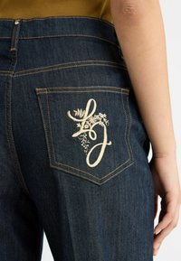 Jeans in denim blu scuro con un design floreale ricamato con le lettere "L" e "J" sulla tasca posteriore destra.