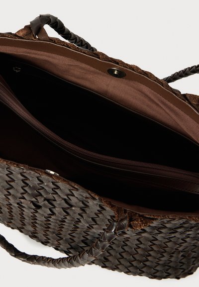 Υφασμάτινη καφέ τσάντα με πλεγμένες δερμάτινες λαβές και ομαλή υφασμάτινη εσωτερική επένδυση, διαθέτει τσέπη με φερμουάρ και κλείσιμο με κουμπί.