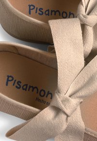 Beige Leinenschuhe mit breiten Stoffbindern und strukturierten Oberflächen. Mit blauer Markenbezeichnung "Pisamon" auf den Einlegesohlen. Schlichtes, abgerundetes Design.