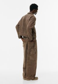 Brun corduroyjakke med cropped design, parret med matchende cargobukser med flere lommer og en afslappet pasform.