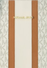 Λευκή και ταμπά δερμάτινη τσάντα χειρός με ανάγλυφο σχέδιο, διακοσμητικό χρυσό λογότυπο και αντίθετες κάθετες ρίγες. Ορατές ραφές λεπτομέρειας.