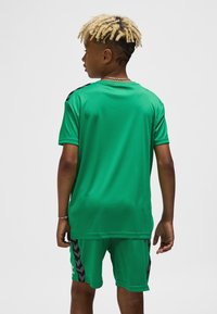 Grönt tr�äningsset med tröja och shorts som har en jämn textur, svarta accentstrimmor på sidorna och en avslappnad passform.