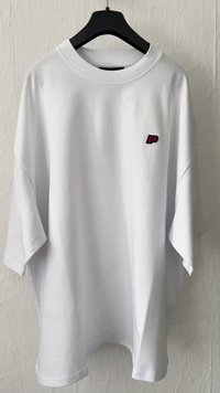 T-shirt bianco oversize in cotone. Presenta un collo rotondo e un piccolo logo nero e rosa sull'area sinistra del petto. Maniche corte.