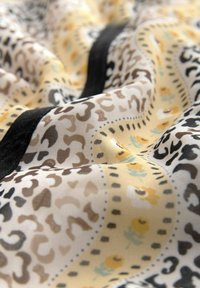 Stoff mit einem gelben, floralen und tierischen Druckmuster, das schwarze und braune Akzente aufweist. Glatte Textur, leicht und mit buntem Design.