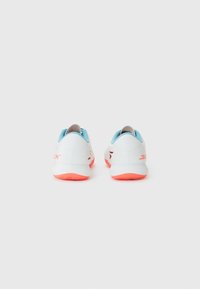 White athletic shoes with a smooth texture, blue accents, and orange soles. Features minimal branding and a streamlined design.