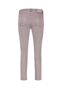 Jeans ajustados en denim de lavanda claro. Presentan una cintura alta, cinco bolsillos y un parche de marca en la parte trasera de la cinturilla. Textura suave.