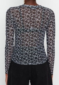 Top a maniche lunghe e trasparente, con una base grigia decorata con macchie leopardate nere e marroni, colletto rotondo e design aderente.