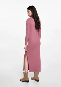 Pitkähihainen, ribattu neulemekko vaaleanpunaisena, sivusaumassa halkio. Yhdistetty vaaleisiin nilkkureihin, joissa on matalat korot ja koristeommellut yksityiskohdat.