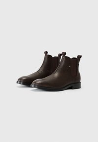 Botas de cuero marrón hasta el tobillo con paneles laterales elásticos y tiradores. Diseño de punta redonda, tacón bajo y detalles minimalistas para un aspecto clásico.