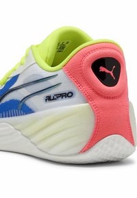 Close-up af en Puma All Pro sneaker med neongul foring, blå accenter, hvid sål og en pink hæl med Puma-logo.