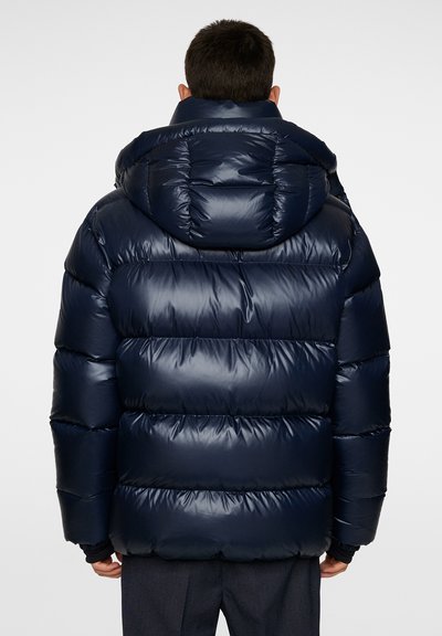 Navy puffer jacket with a shiny, padded exterior. Features a large hood and ribbed cuffs, designed with horizontal quilting for insulation.