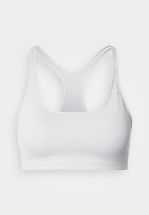 Brassière de sport blanche à texture lisse, avec un logo rond en relief au centre et des bretelles racerback réglables.