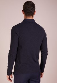 Pusero navy pitkät hihat, jossa on teksturoitu kangas, kaulus, slim fit ja ribbaus hihansuissa, takaa näkyvissä.