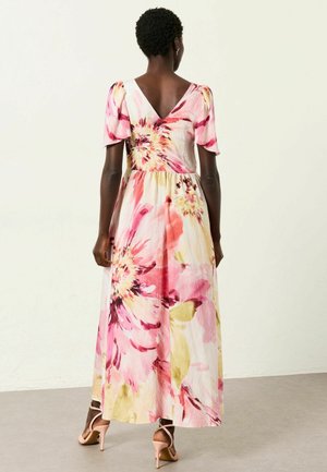 Vaaleanpunainen, keltainen ja valkoinen kukallinen maksimekko, jossa on puffy-hihat ja V-muotoinen selkä. Valmistettu kevyestä kankaasta, jossa on levenevä hame.