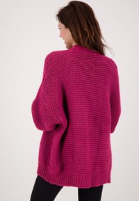 Overmaat gebreide cardigan in levendig fuchsia. Geweven patroon, verlaagde schouders, geribde manchetten en zoom, en een ronde halslijn.