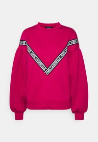 Magenta bluza z bufkami, z dekoltem w kształcie V oraz czarnym pasem z logo "Karl Lagerfeld" na piersi.