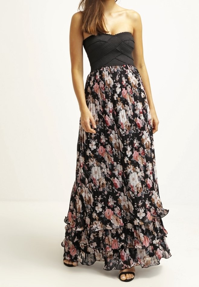 Vestido maxi con un corpete negro ajustado, falda acampanada de flores en negro, rosa y crema, con volantes y un diseño sin tirantes.