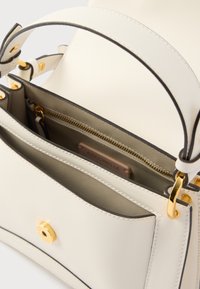 Witte leren handtas met gouden details, een ritssluiting en een vlakke zak. Contrasterende zwarte stiksels benadrukken het ontwerp.