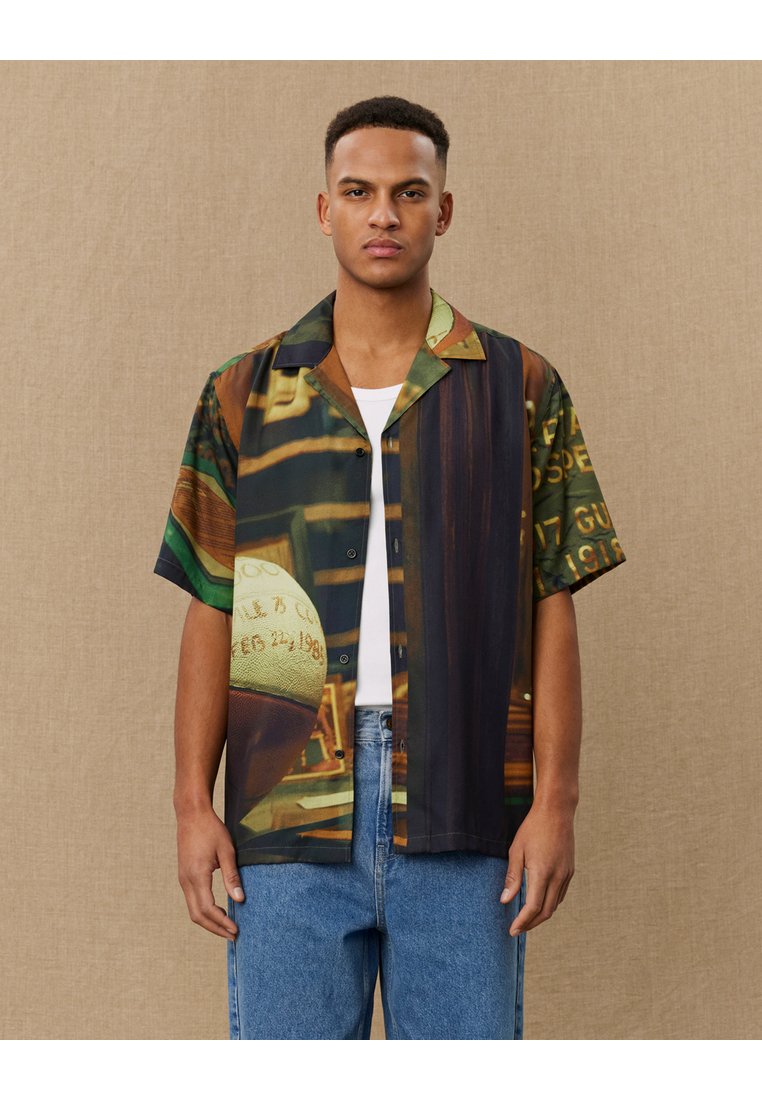 Short-sleeve shirt with a multicolored photographic print, featuring greens, browns, and yellows. Made from lightweight fabric, buttoned front.