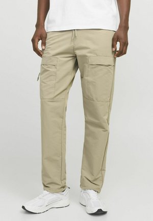 Pantalones cargo beige hechos de material ligero, con múltiples bolsillos laterales, una cinturilla con cordón y piernas ajustadas.