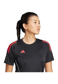 Maglietta sportiva nera con strisce rosse sui lati delle spalle, caratterizzata da un collo rotondo e logo. Tessuto liscio e materiale leggero.