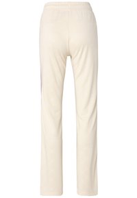 Crèmekleurige trainingsbroek met een gladde textuur, voorzien van een subtiel logo-patroon over de gehele broek en een elastische tailleband voor extra comfort.