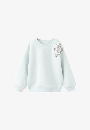 Svetlo modra majica z okroglim ovratnikom, dolgimi rokavi in cvetličnim vezenjem na levem rami.